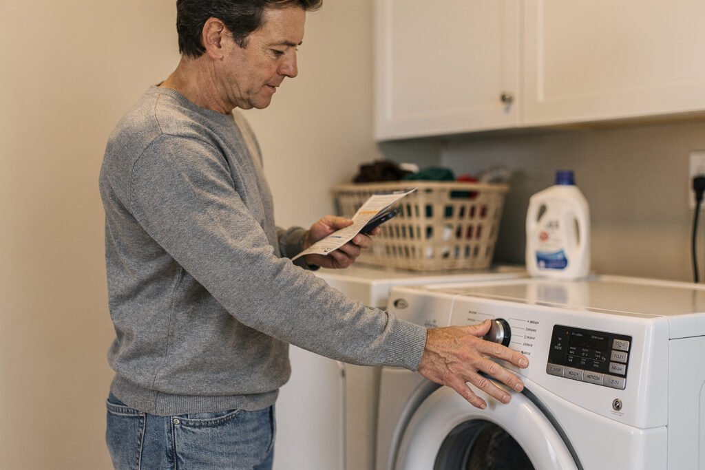 Person checking simple instructions while standing near home appliances, suggesting everyday troubleshooting at home