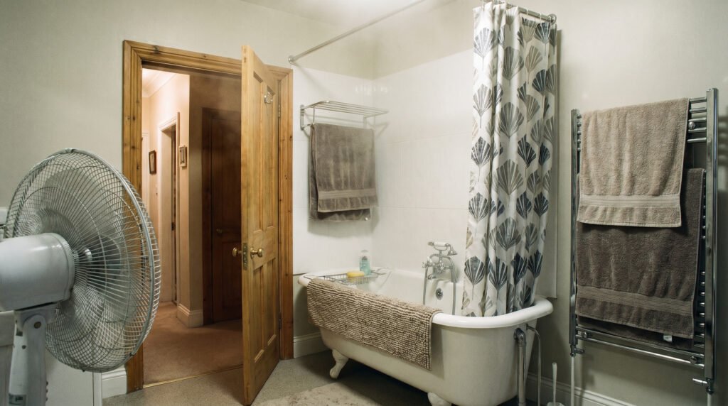 Bathroom drying routine after a shower with fan running, door open, and wet items spread out to dry